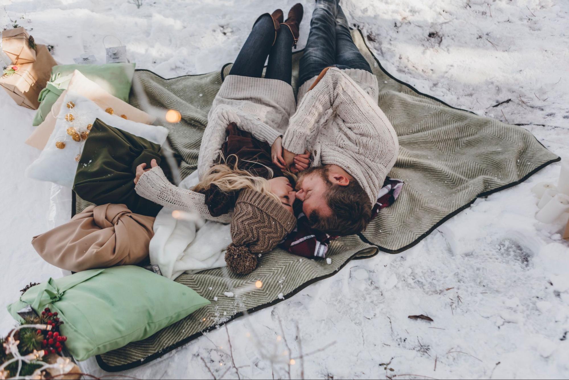 man and woman cuddling on blanket in snow